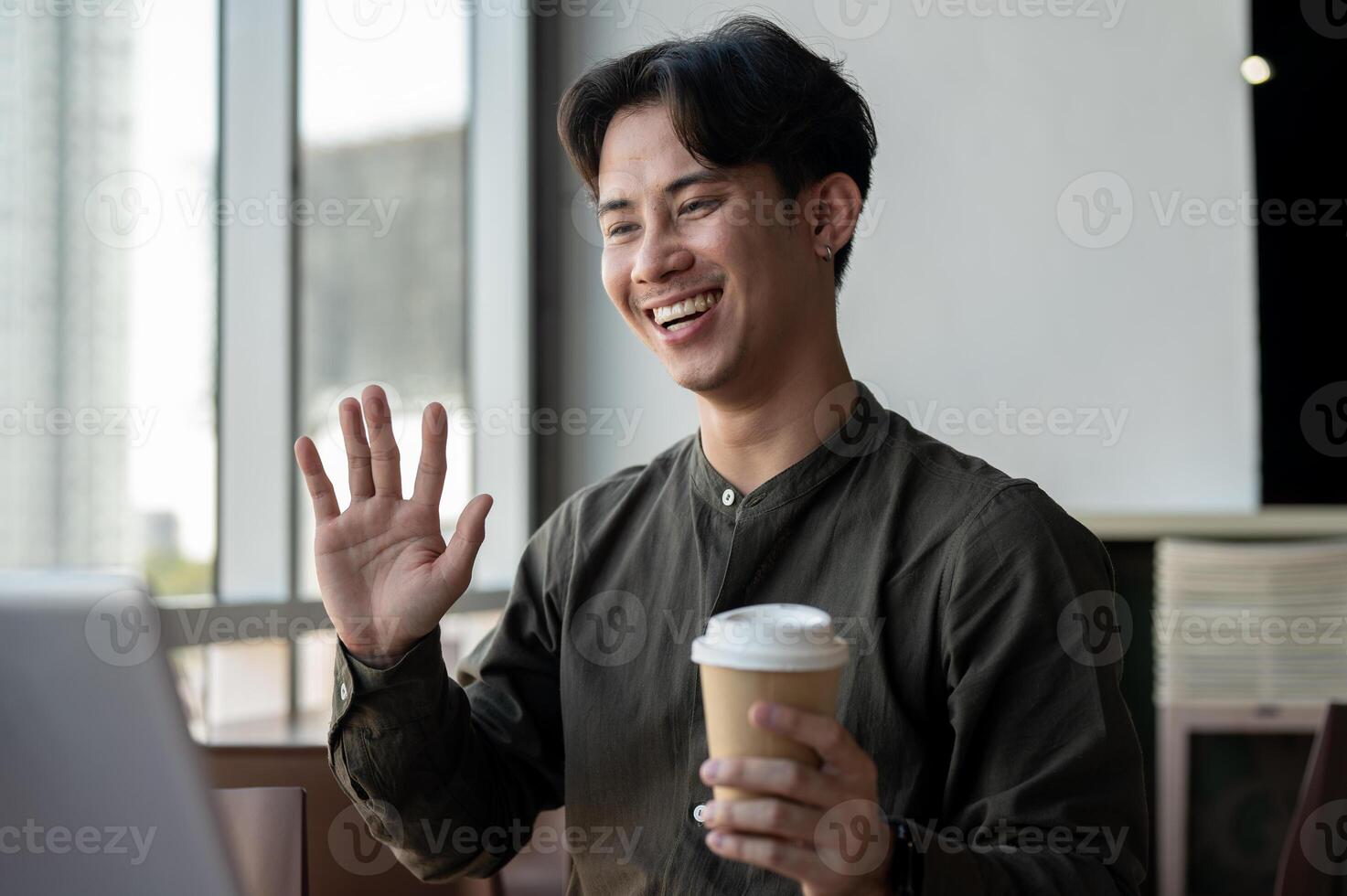 A cheerful businessman working remotely from a coffee shop, having an online meeting with his team. photo