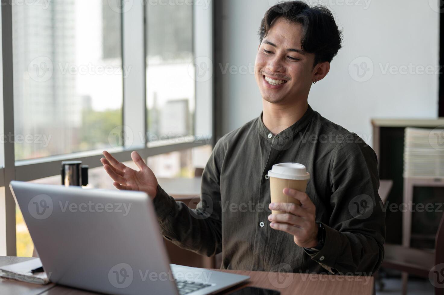 A cheerful businessman working remotely from a coffee shop, having an online meeting with his team. photo