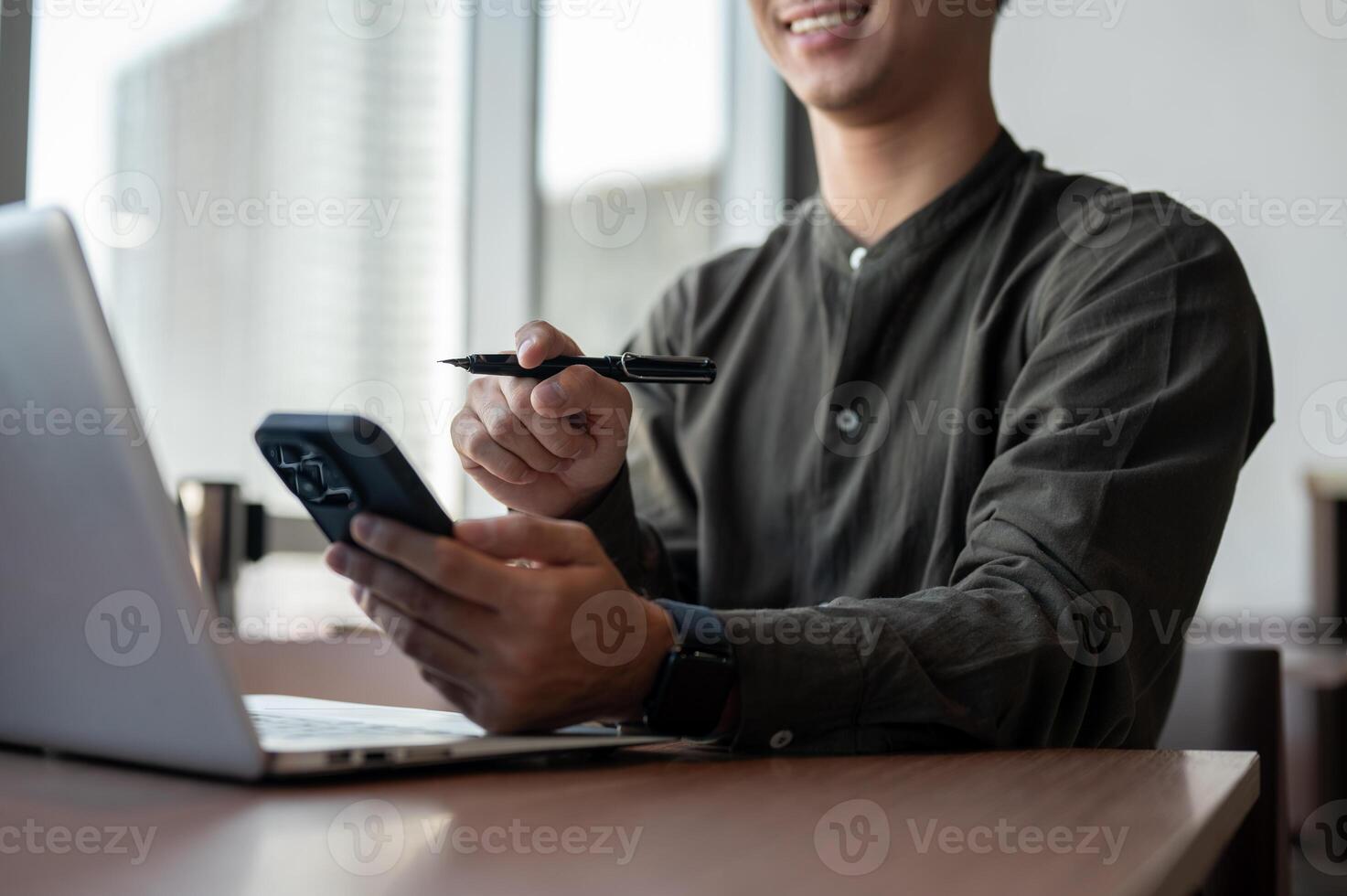 A close-up of an Asian businessman using his smartphone while working in a modern office. photo