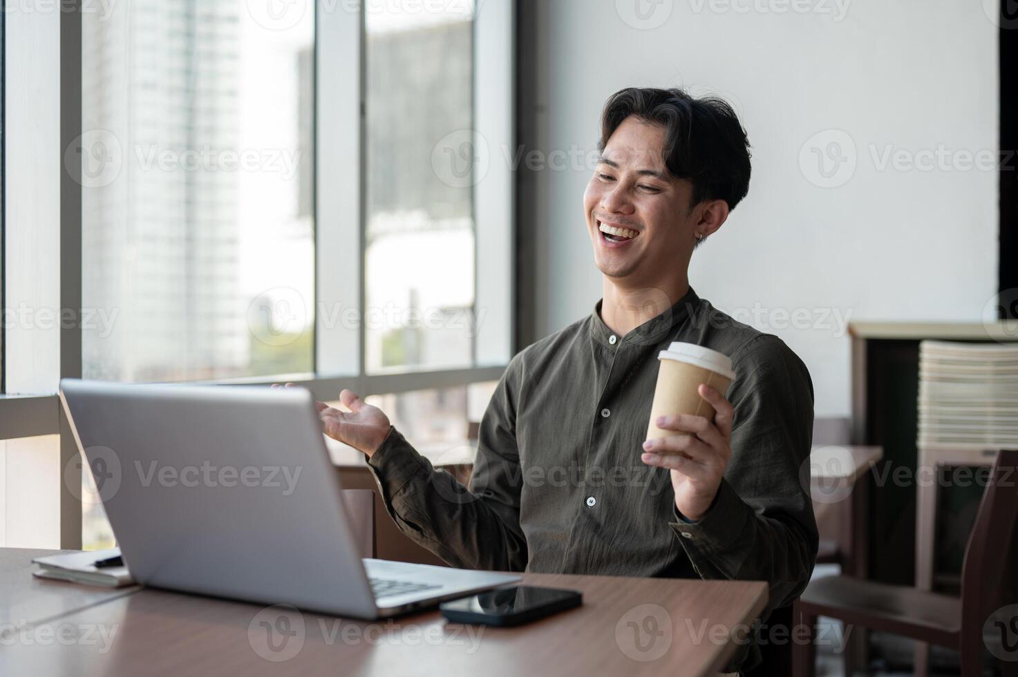 A cheerful businessman working remotely from a coffee shop, having an online meeting with his team. photo