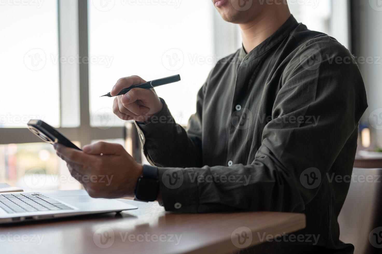 A close-up of an Asian businessman using his smartphone while working in a modern office. photo