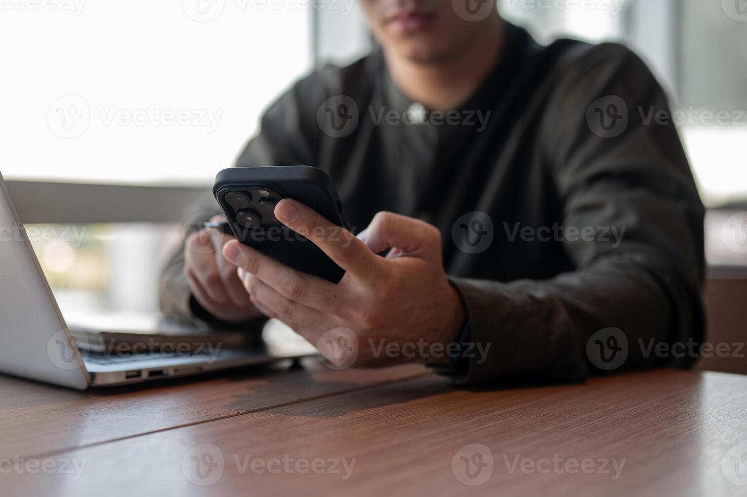 A close-up of a businessman using his smartphone at a table in the office. photo