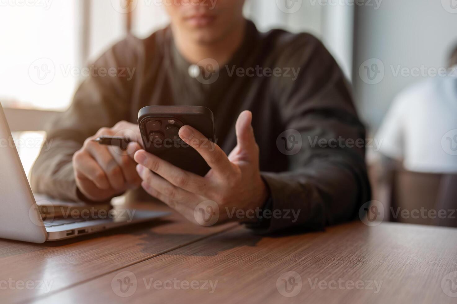 A close-up of a businessman using his smartphone at a table in the office. photo
