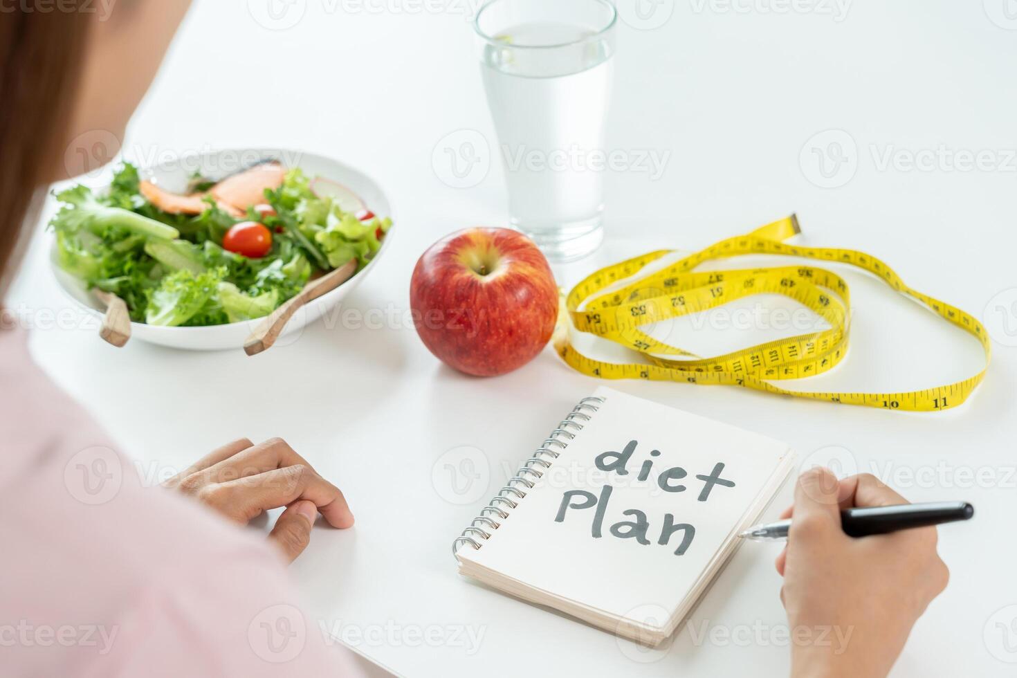 Woman choose healthy food for diet. Healthy food and fatty food separated on table with measuring tape. Lose weight, balance, control, reduce fat, low calorie, routine, exercise, body shape. photo