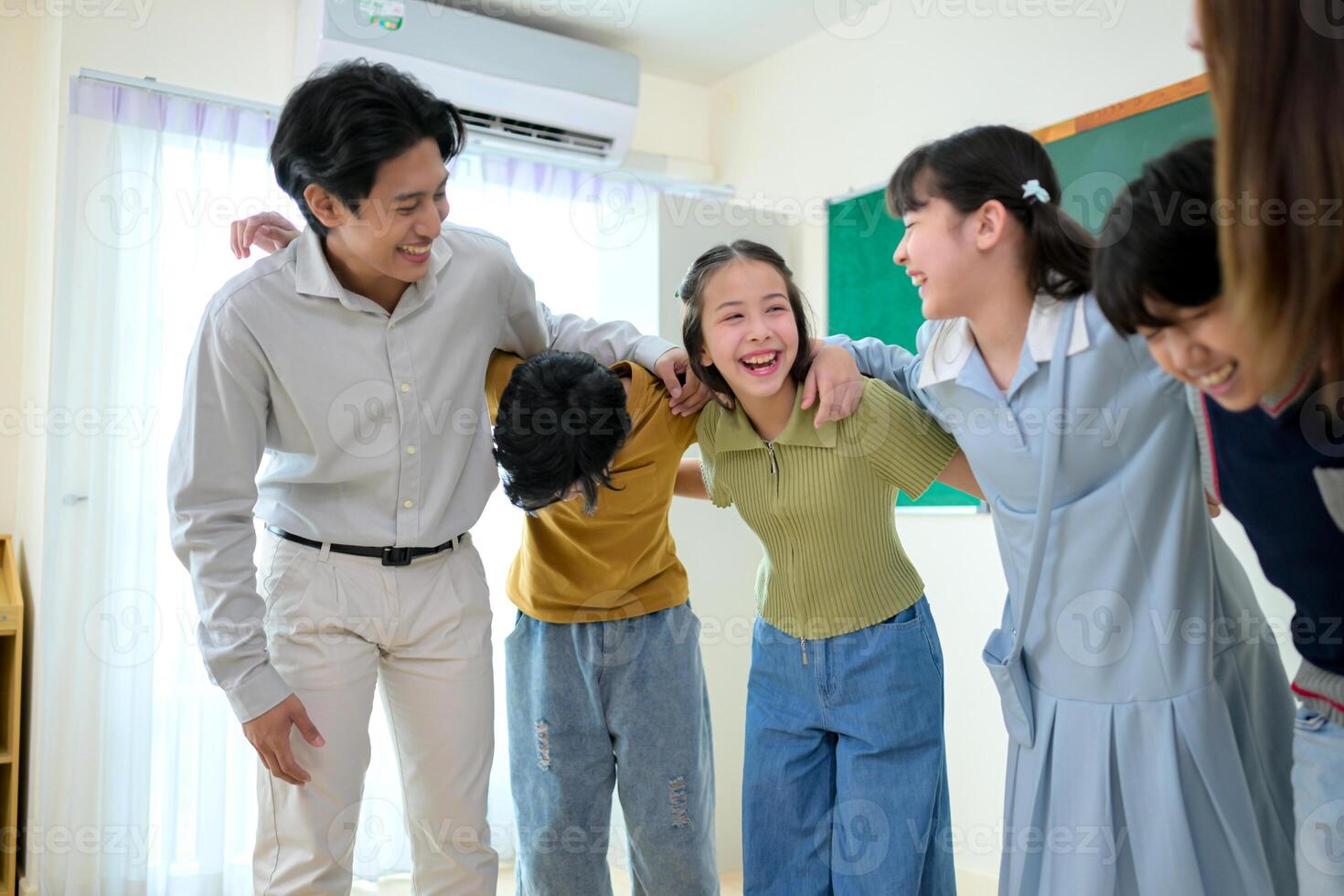 Portrait of a teacher and kids in a classroom where children have pleasure learning photo
