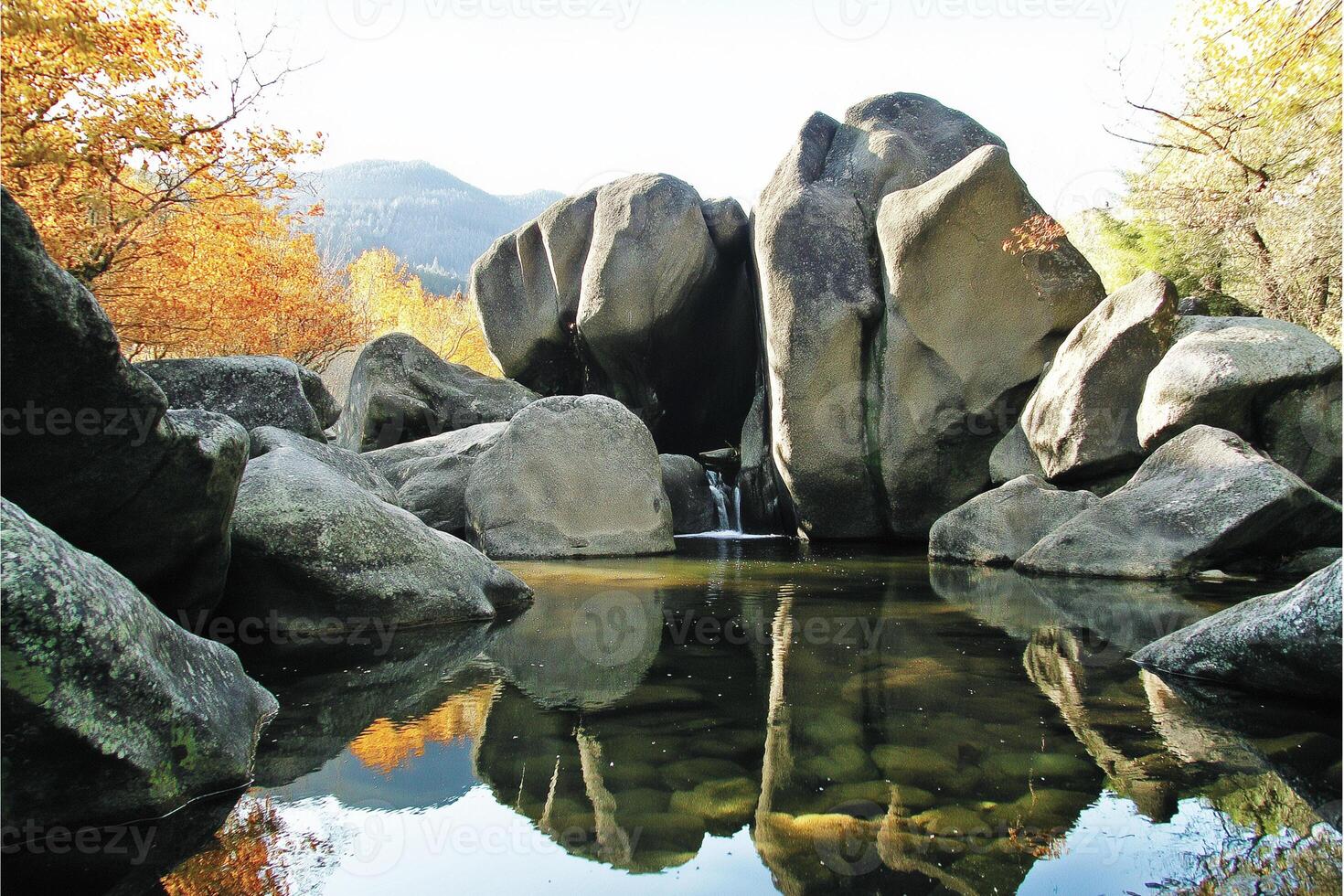 Serene waterfall nestled amongst ancient rocks, a tranquil autumn scene. photo