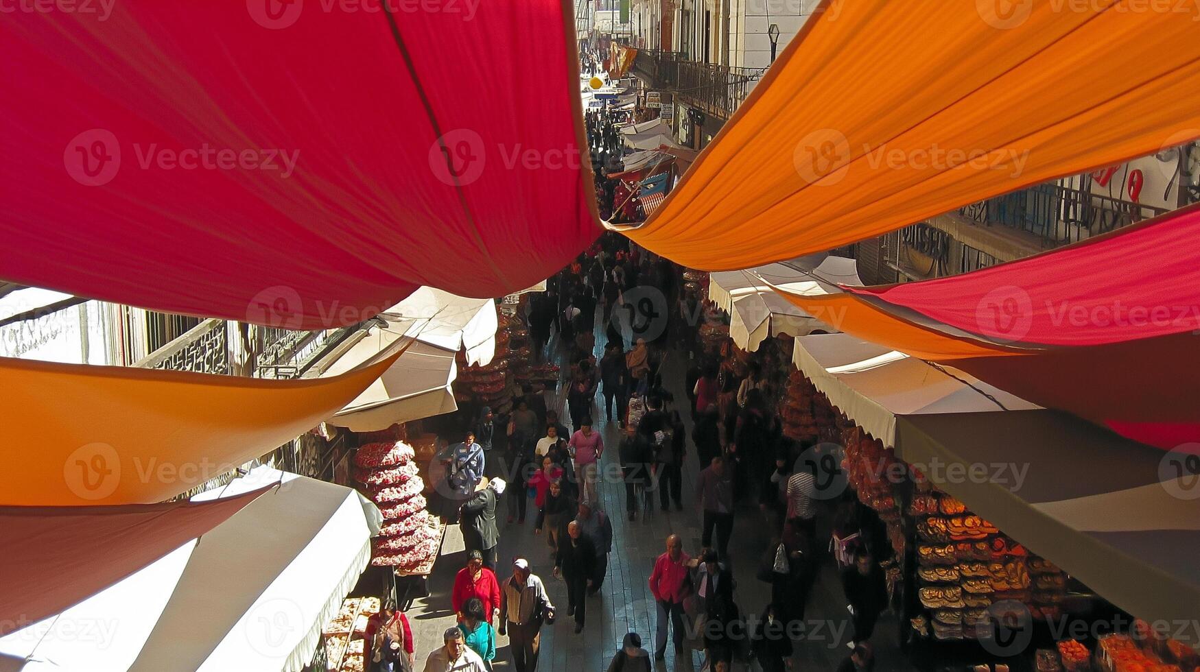 Colorful awnings shade a bustling market street. photo