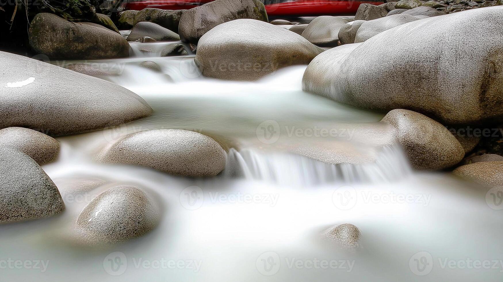 A river flowing through a rocky area with a red canoe photo