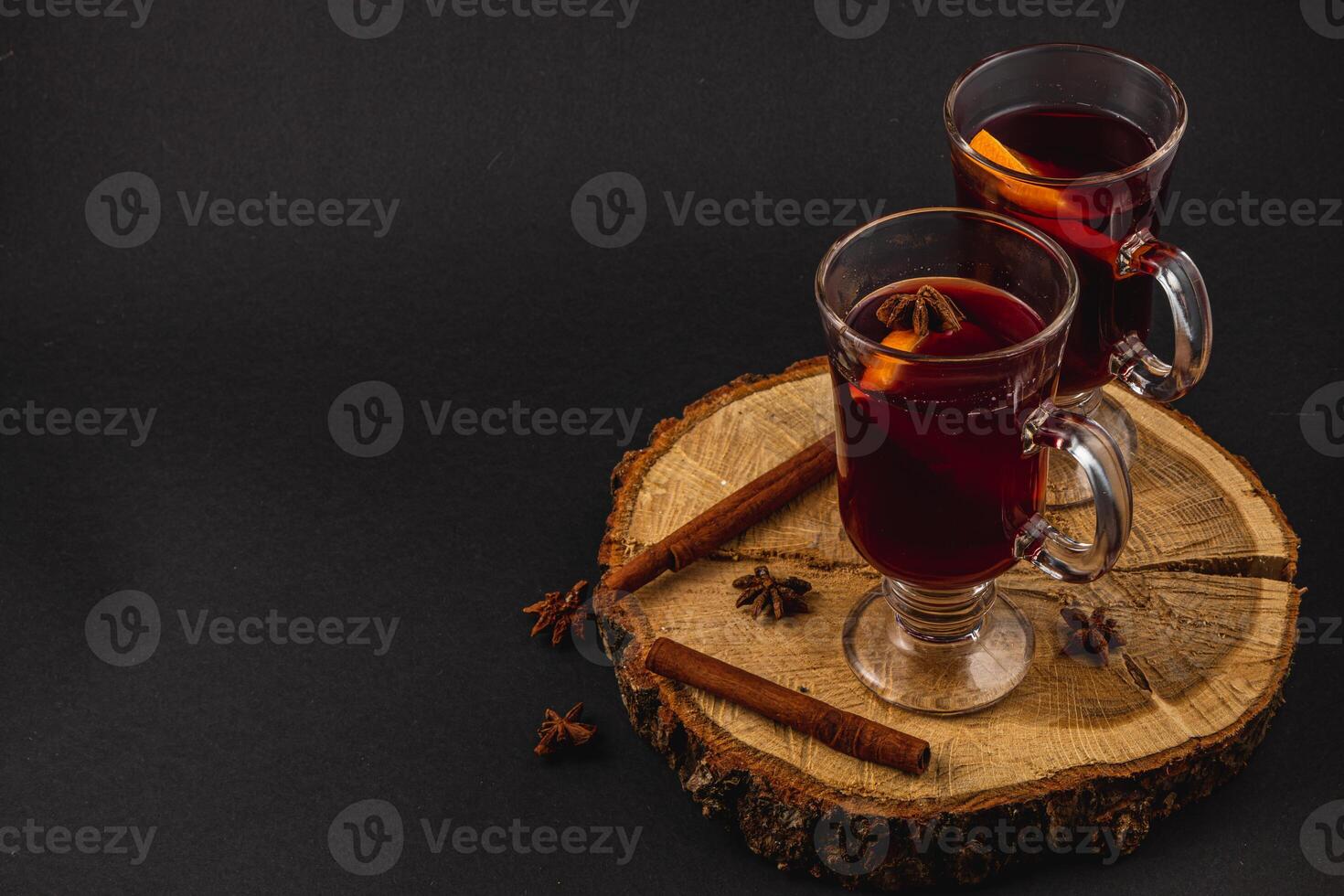 aromatic mulled wine with spices on a piece of wood on a black background photo