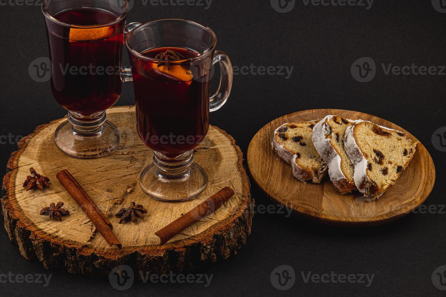 aromatic mulled wine with fresh stollen on a wooden plate on a black background photo