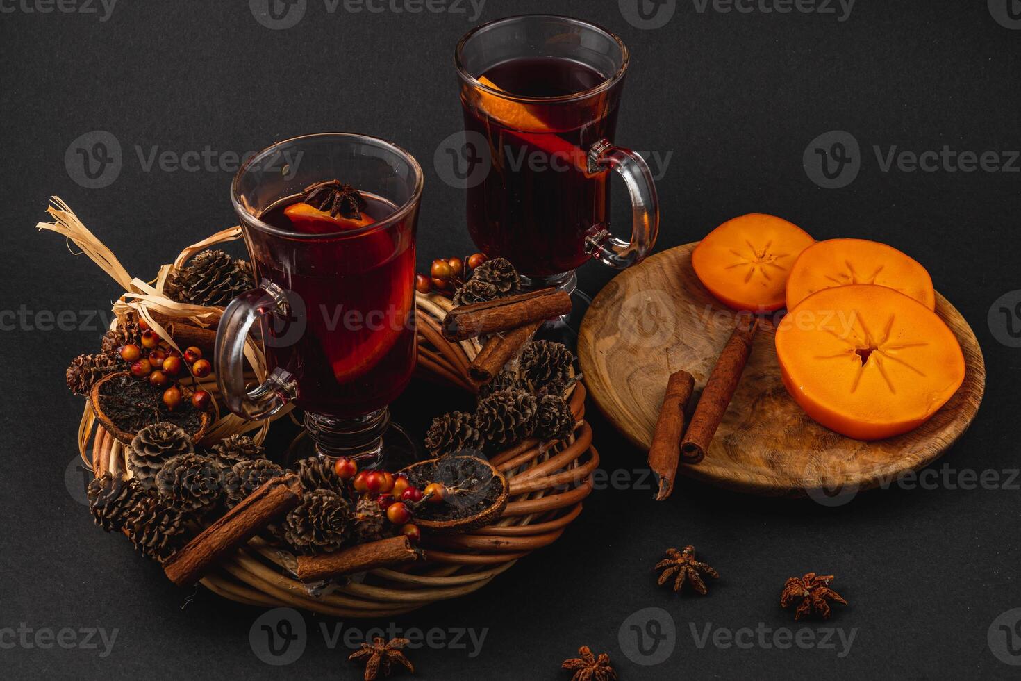 Delicious mulled wine with spices and sweet persimmons on a wooden plate photo