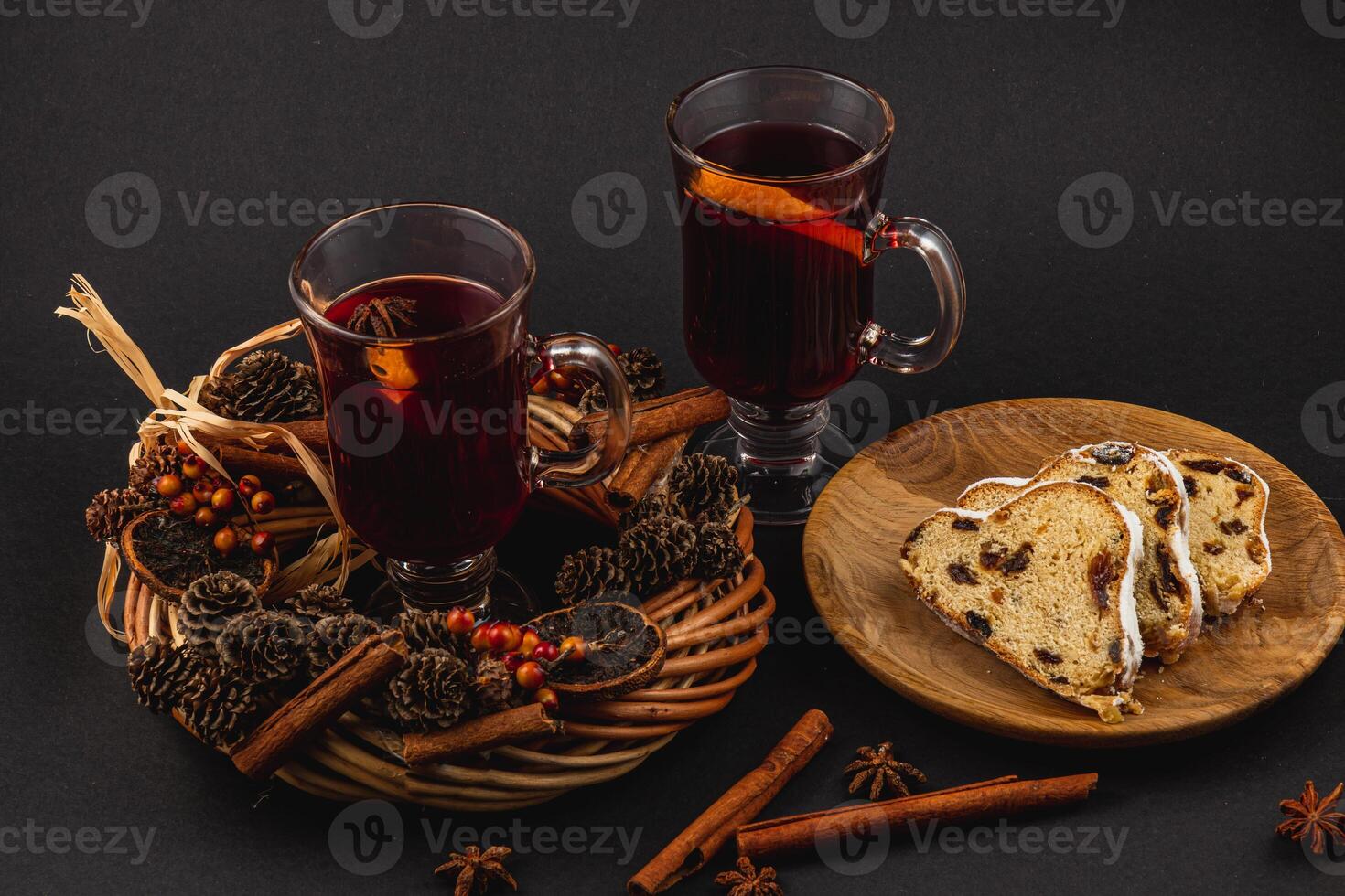 aromatic mulled wine with fresh stollen on a wooden plate on a black background photo