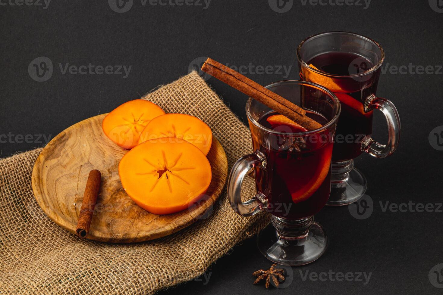 Festive Christmas mulled wine with sweet persimmons on a black background photo