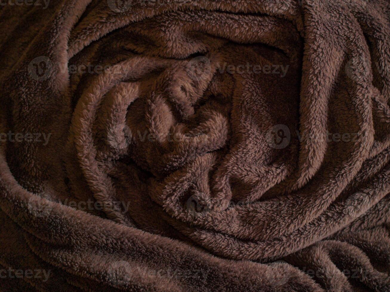 Cozy Fleece Blanket Rolled Up in Warm Brown Tones, Concept of Comfort, Relaxation, and Home Decor. Background, Texture photo