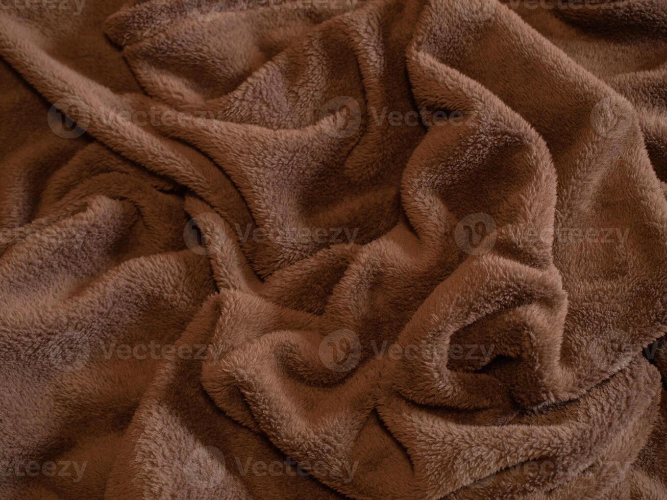 Close-up of soft brown fleece fabric with folds and texture. Concept of cozy materials, warmth, comfort, and textile design. Background, Texture photo