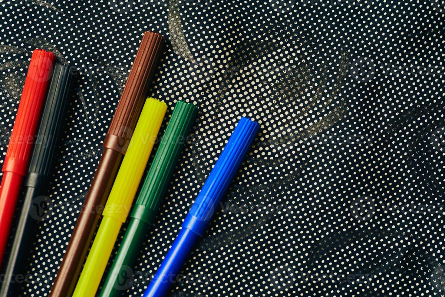 Multicolored felt tip pens markers for drawing on dark spotted fabric photo