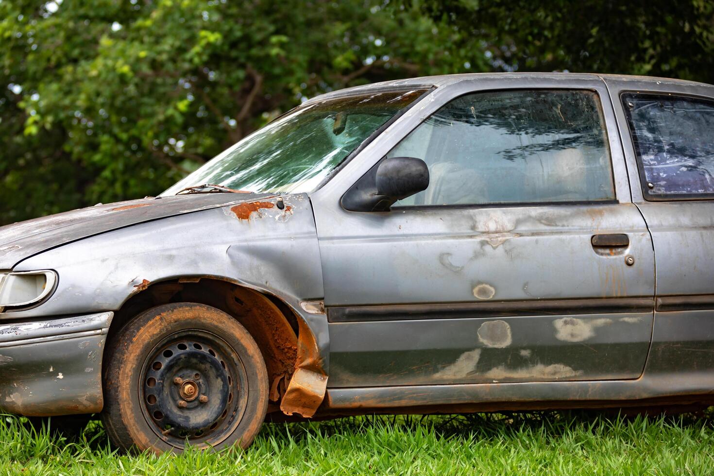 Old, weather-damaged, rusty abandoned car photo