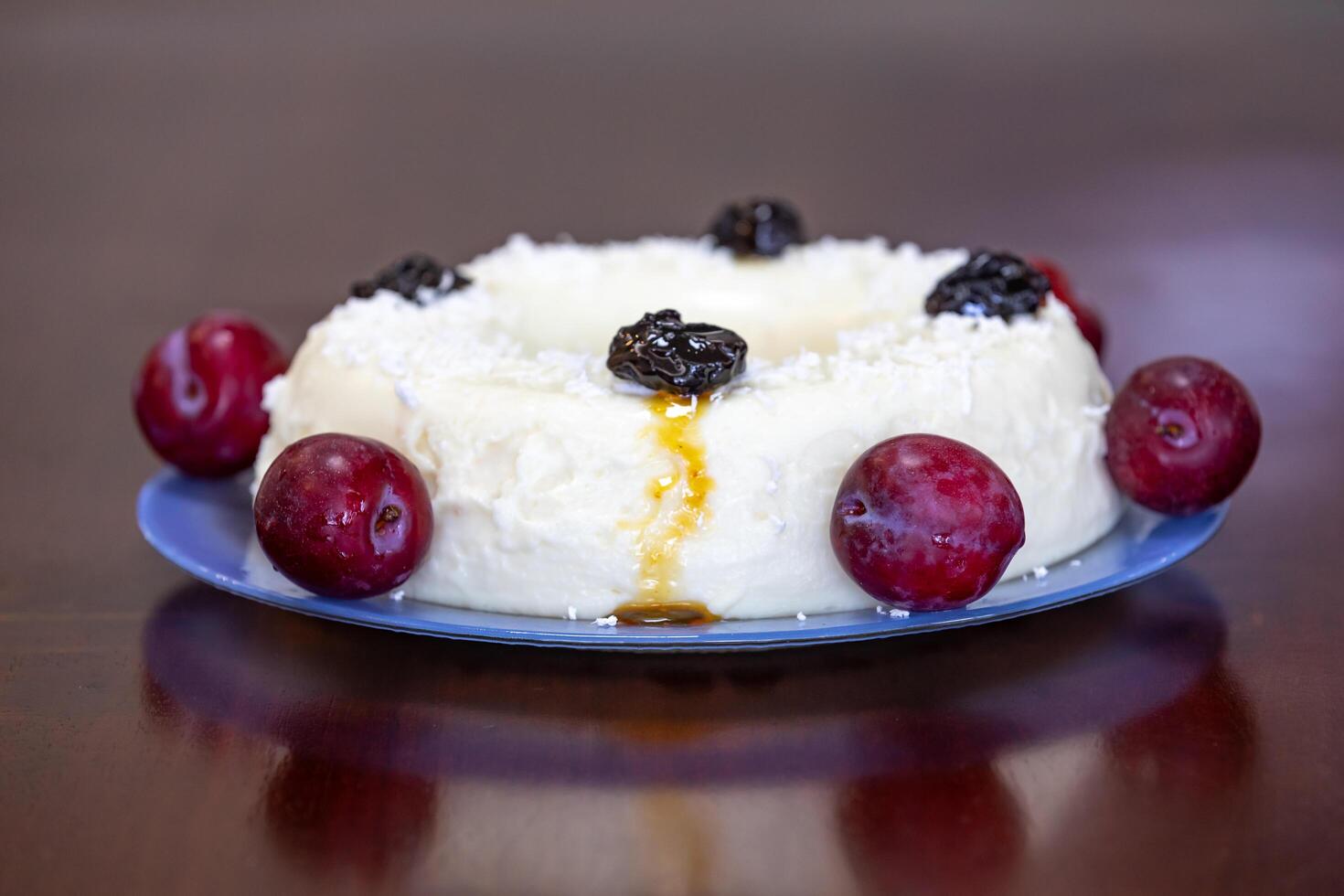 Traditional Brazilian coconut flan dessert known as manjar branco, manjar de coco and manjar dos deuses. Served with plum syrup. photo