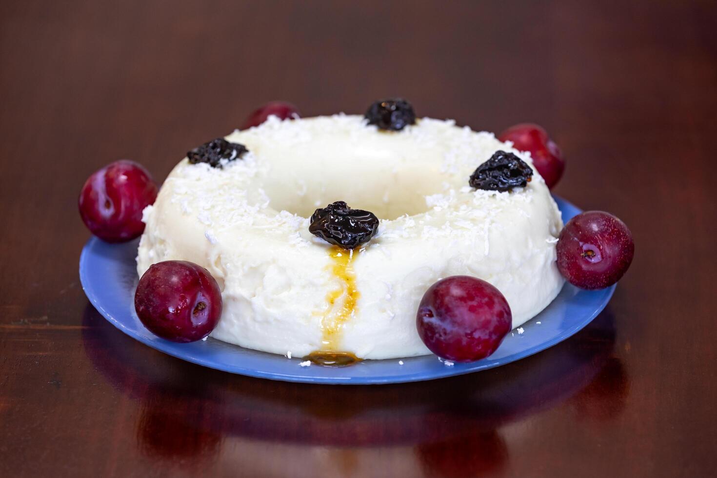 Traditional Brazilian coconut flan dessert known as manjar branco, manjar de coco and manjar dos deuses. Served with plum syrup. photo