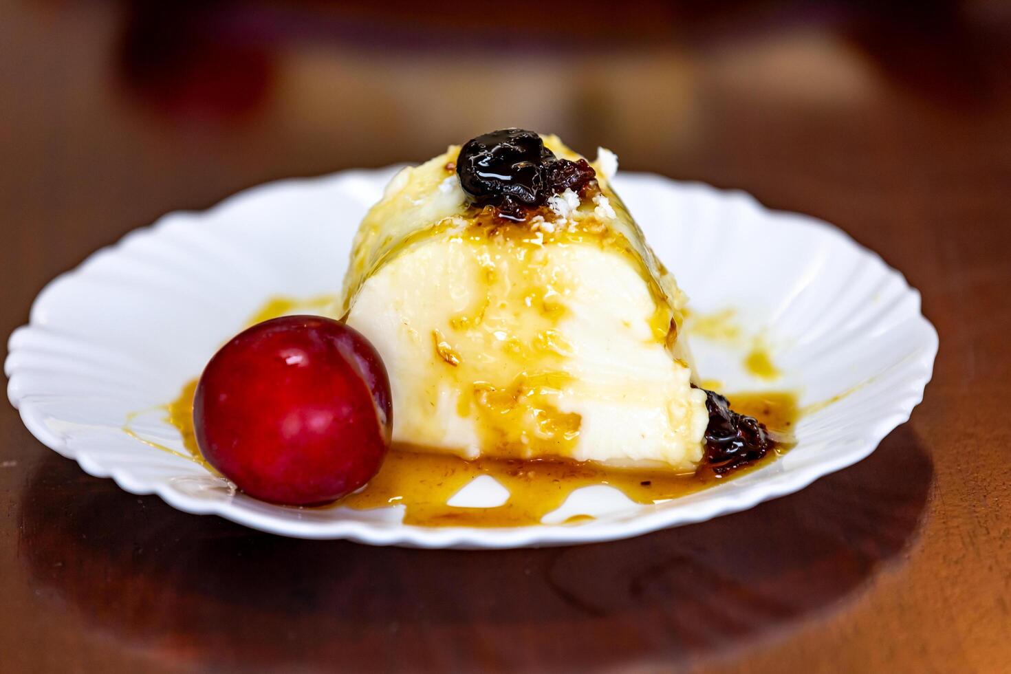 Traditional Brazilian coconut flan dessert known as manjar branco, manjar de coco and manjar dos deuses. Served with plum syrup. photo