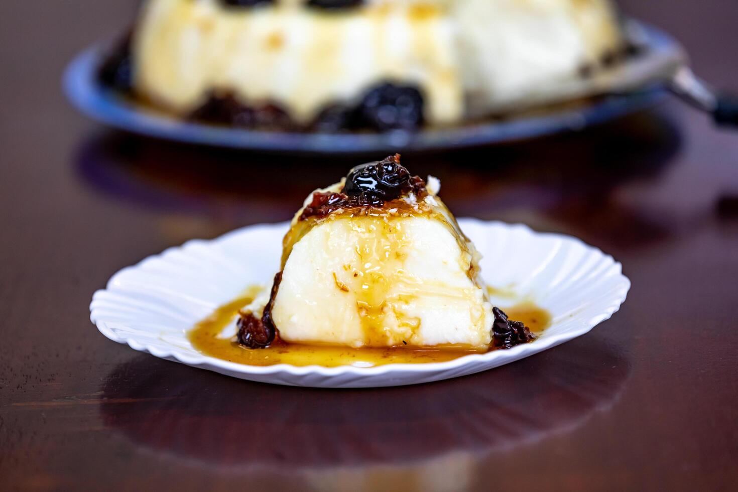 Traditional Brazilian coconut flan dessert known as manjar branco, manjar de coco and manjar dos deuses. Served with plum syrup. photo