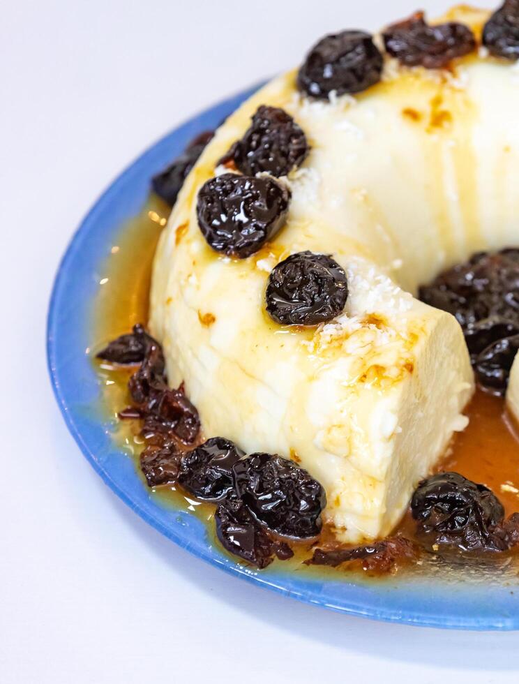 Traditional Brazilian coconut flan dessert known as manjar branco, manjar de coco and manjar dos deuses. Served with plum syrup. photo