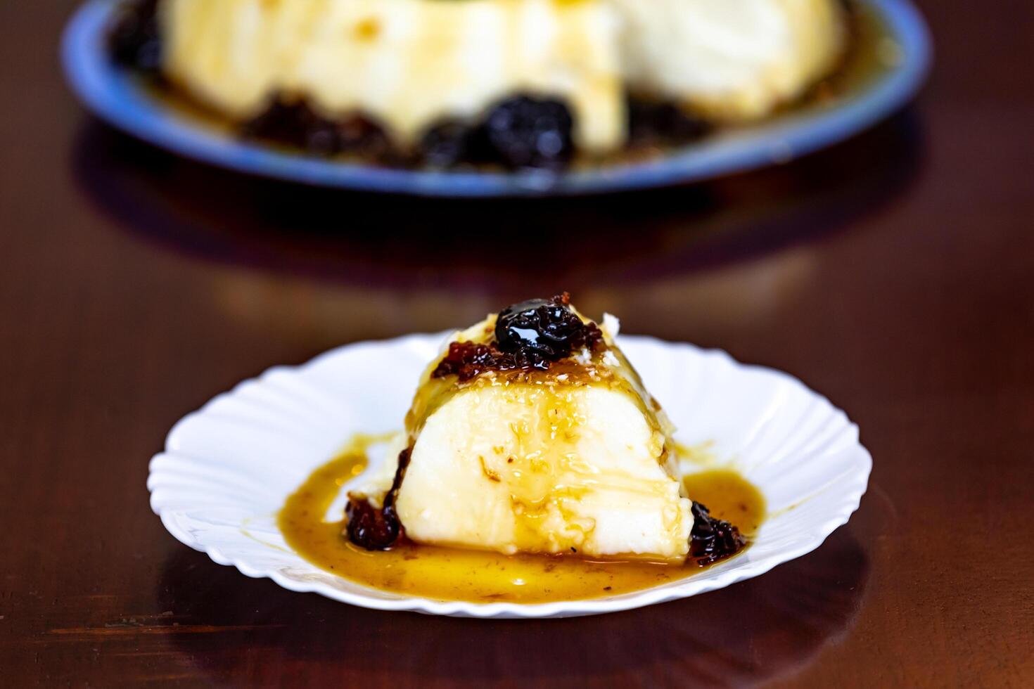 Traditional Brazilian coconut flan dessert known as manjar branco, manjar de coco and manjar dos deuses. Served with plum syrup. photo