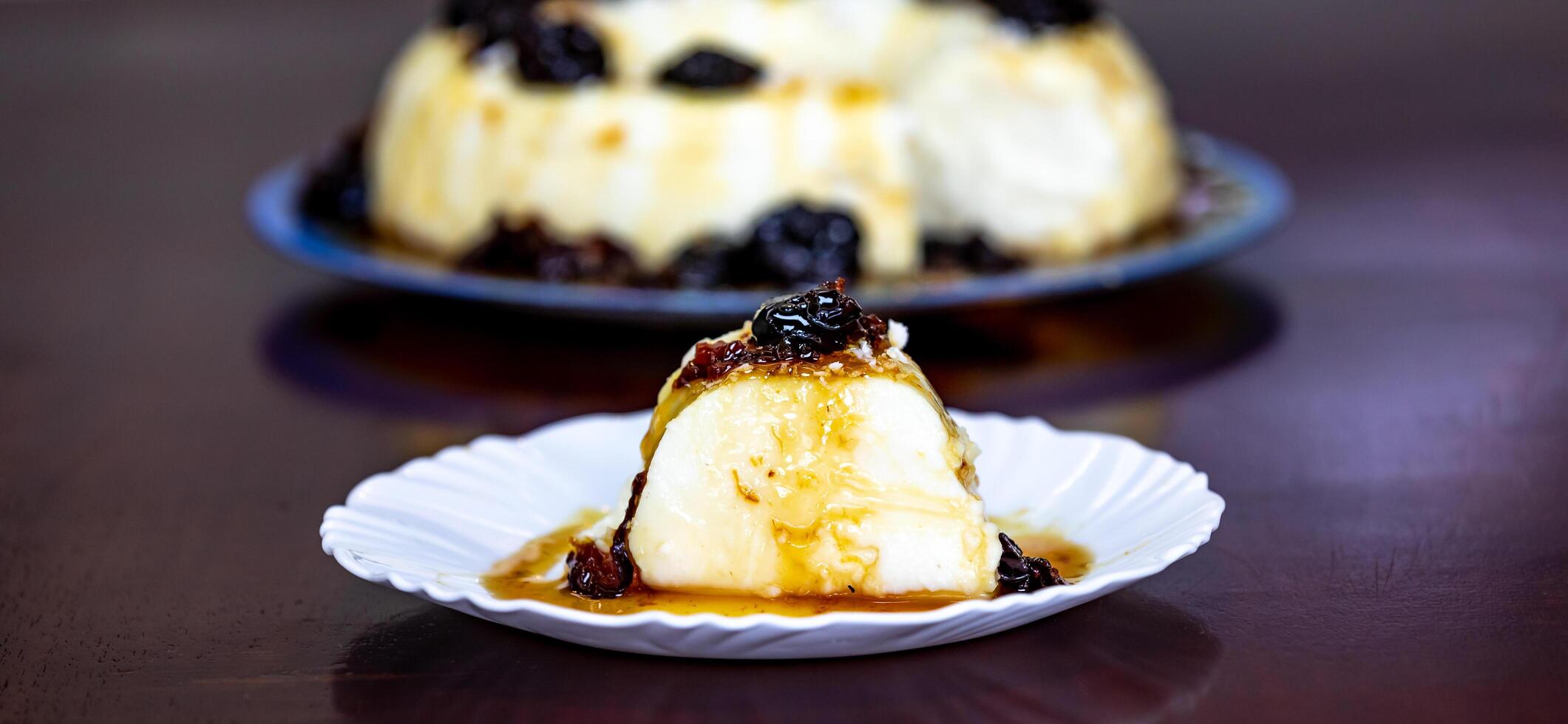 Traditional Brazilian coconut flan dessert known as manjar branco, manjar de coco and manjar dos deuses. Served with plum syrup. photo