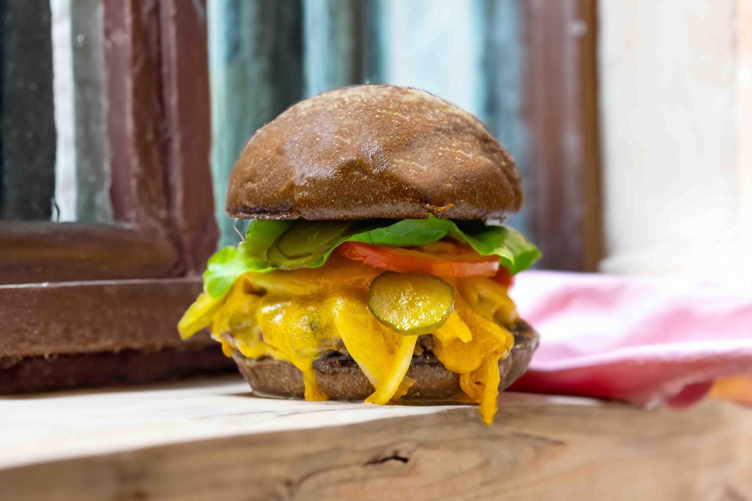 Traditional rustic burger sandwich with cheddar cheese, vegetables and Australian bread in creative photography and cozy village setting photo