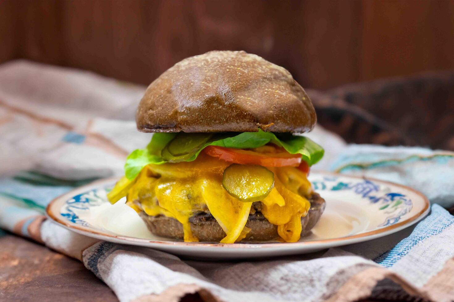 Traditional rustic burger sandwich with cheddar cheese, vegetables and Australian bread in creative photography and cozy village setting photo