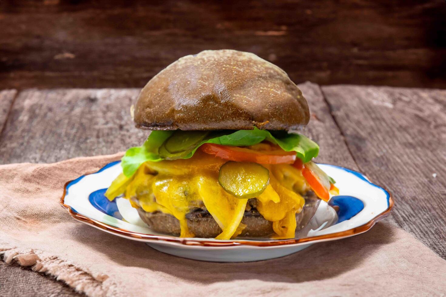 Traditional rustic burger sandwich with cheddar cheese, vegetables and Australian bread in creative photography and cozy village setting photo