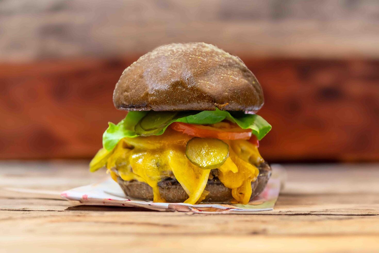 Traditional rustic burger sandwich with cheddar cheese, vegetables and Australian bread in creative photography and cozy village setting photo