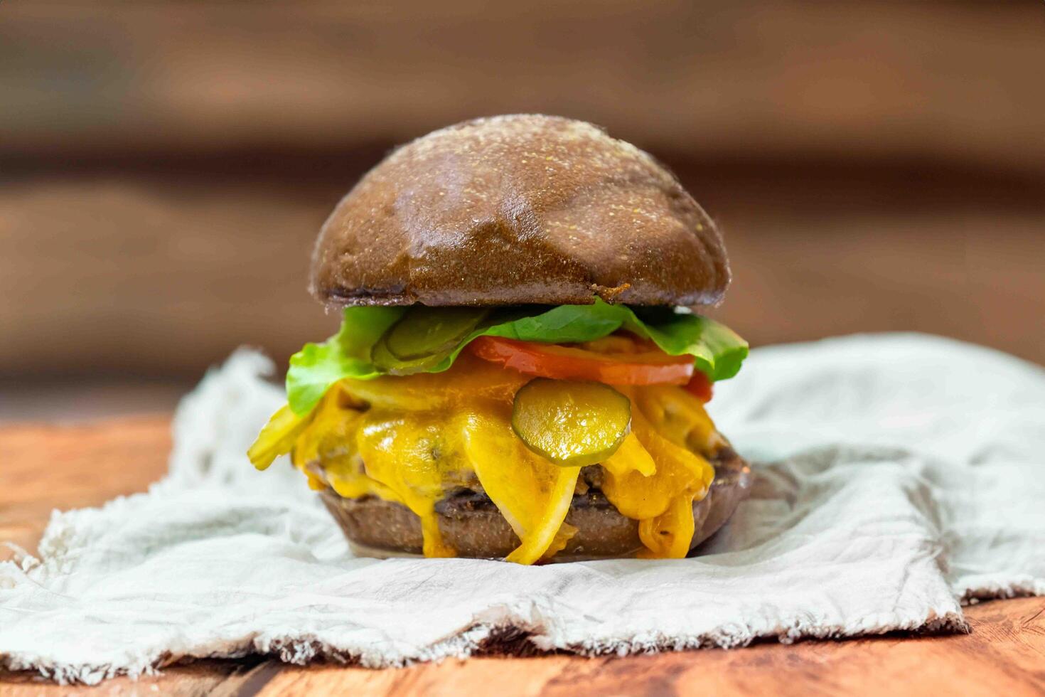 Traditional rustic burger sandwich with cheddar cheese, vegetables and Australian bread in creative photography and cozy village setting photo