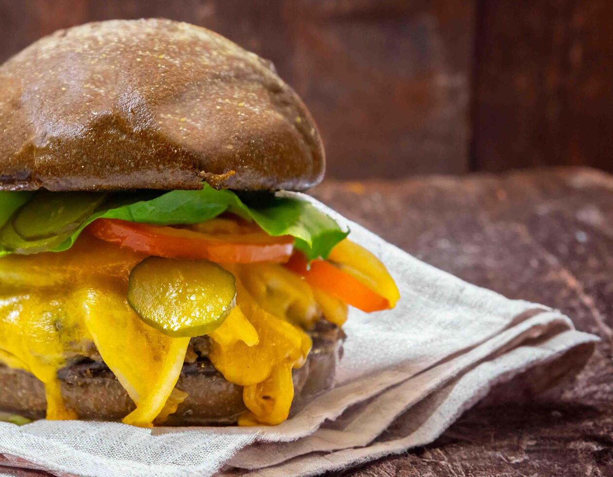 Traditional rustic burger sandwich with cheddar cheese, vegetables and Australian bread in creative photography and cozy village setting photo