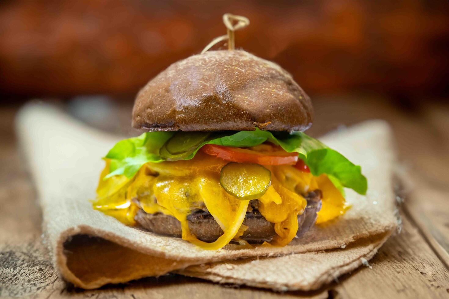 Traditional rustic burger sandwich with cheddar cheese, vegetables and Australian bread in creative photography and cozy village setting photo