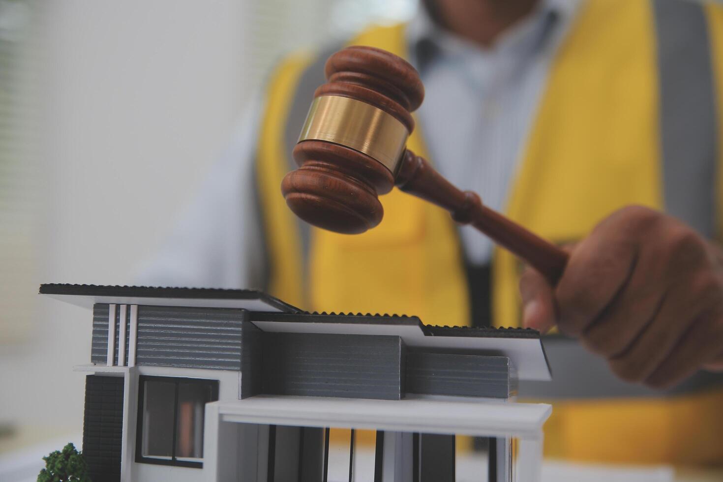 Judge gavel on building blueprint plans with a yellow safety helmet in the background. law that deals with matters relating to building construction, engineering. Construction law concept. photo