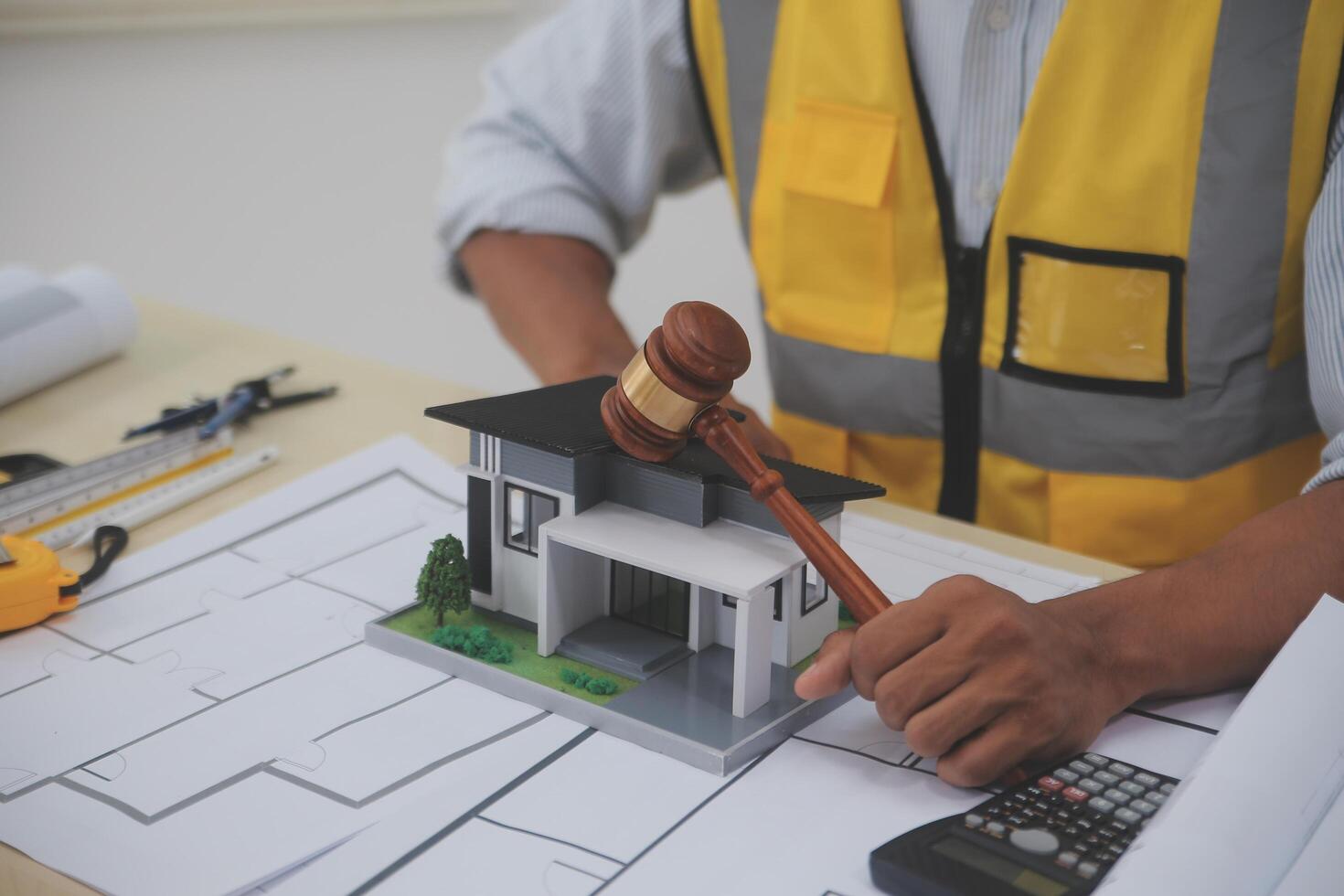 Judge gavel on building blueprint plans with a yellow safety helmet in the background. law that deals with matters relating to building construction, engineering. Construction law concept. photo