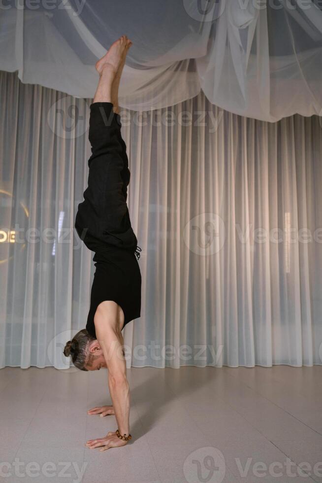 A man stands upside down on his hands in the gym photo