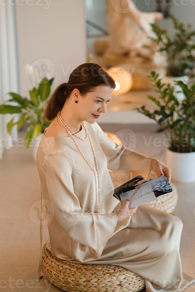 Girl in beige dress with beads with a fan of Tarot cards indoors . Tarot cards in the hands of a fortune teller photo