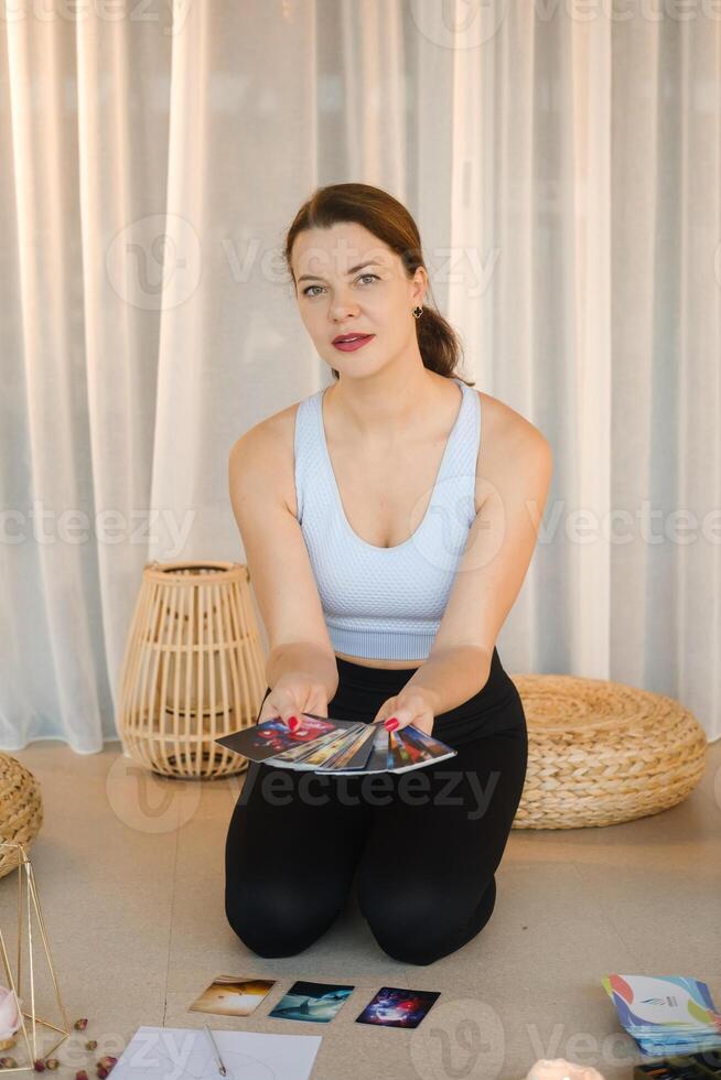 A sporty girl lays out Tarot cards indoors. Tarot cards in the hands of a fortune teller photo