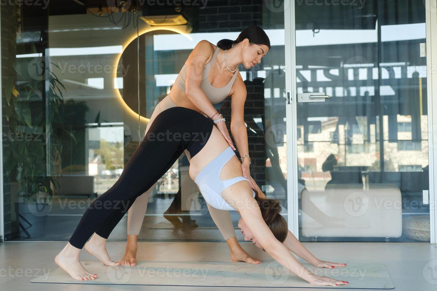 A personal yoga instructor helps the girl do the exercise photo