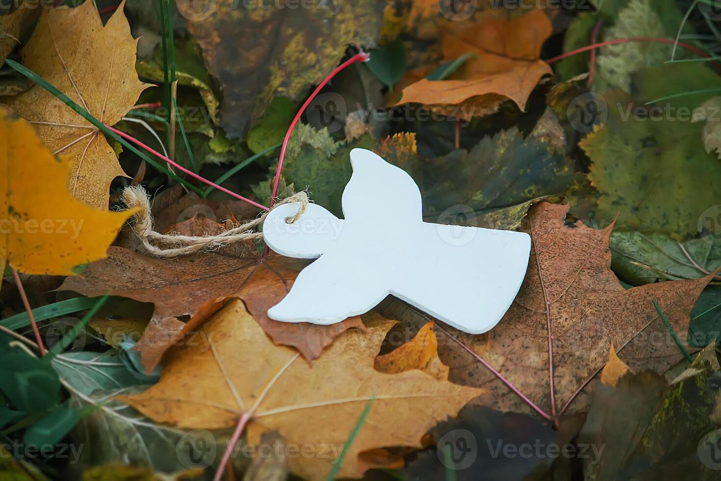 Wooden decoration angel white figure on fall leaves background photo