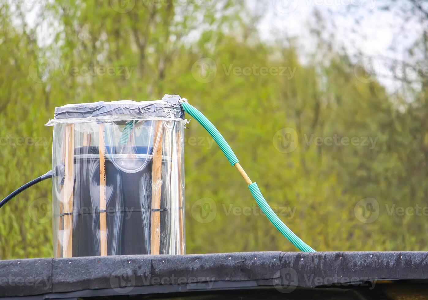 The barrel with water on a roof of homemade outside shower. photo