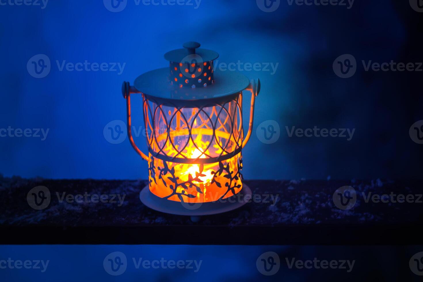 Decorative Christmas lantern with burning candle hanging on snow-covered fir- tree branch in a winter park. New year festive card, poster, postcard design. photo