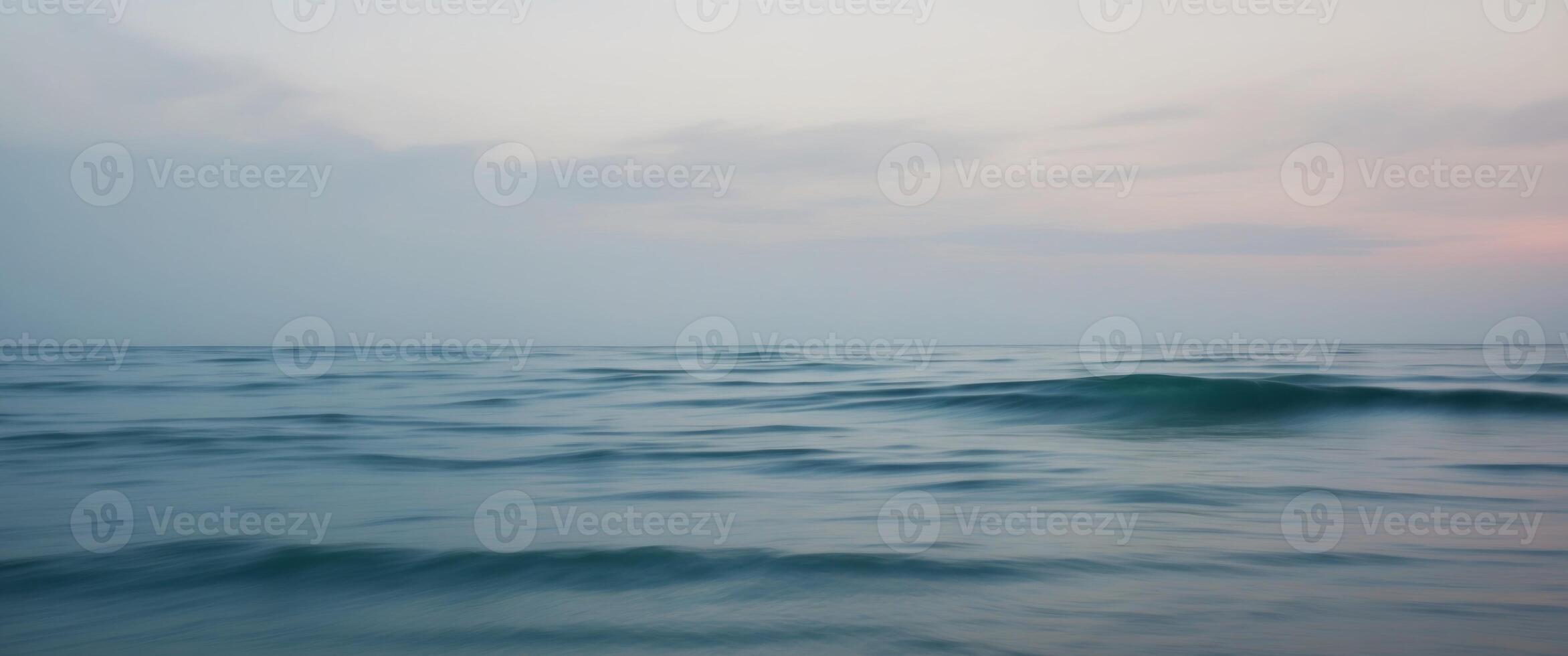 Calm blue ocean water under overcast sky in twilight. photo