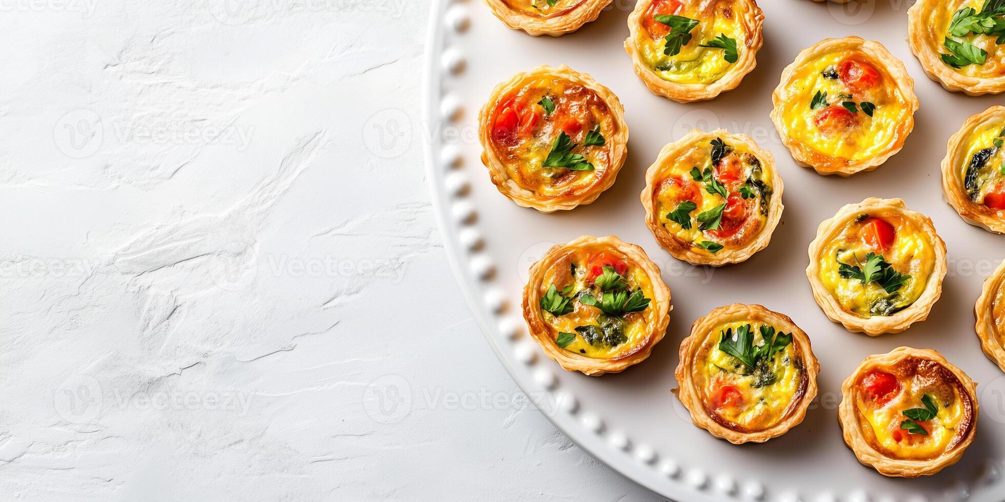 Mini quiches arranged in an organized pattern on a white platter, food setting photo