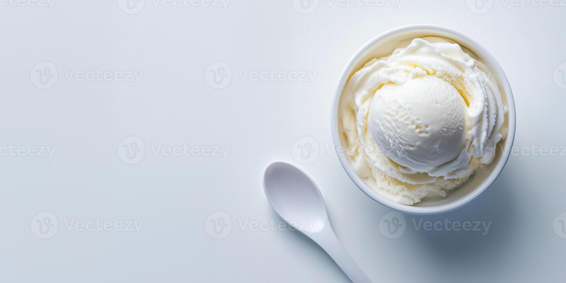Small bowl of vanilla ice cream next to a simple white spoon, food setting photo