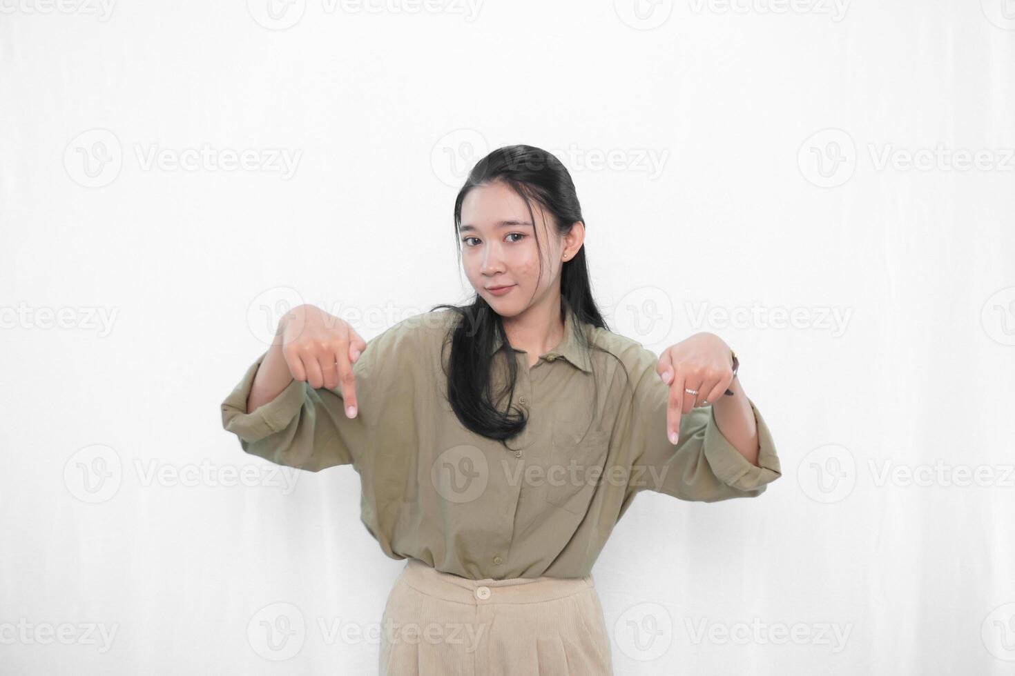 The smiling expression of an Indonesian Asian woman in green and pointing down photo