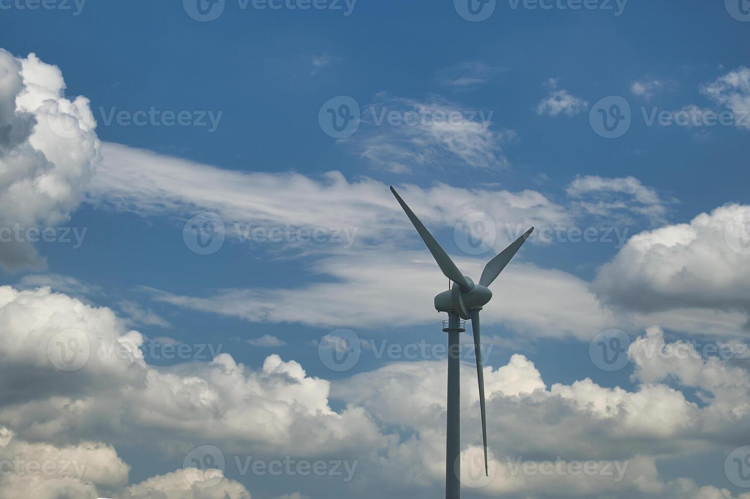 Wind turbine against a backdrop of cloudy and clear blue sky capturing renewable energy photo