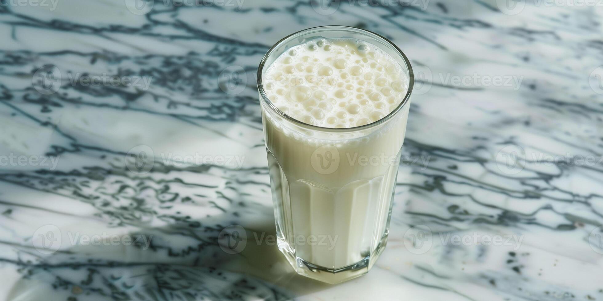Clear glass of kefir with visible bubbles, sitting on a marble countertop, food photography photo